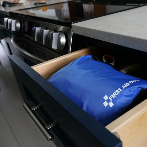 Front view of blue First Aid Only emergency kit pouch in an open kitchen drawer