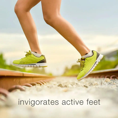 Person running on a railway track wearing lime green athletic shoes, with a blurred scenic landscape in the background.