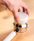 Top Shelf Hella Smooth 58Mm Stainless Steel Espresso Tamper Set With Spring Loaded Impact Hammer held over portafilter.