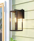 Dusk To Dawn Photocell Sensor Black Outdoor Wall Lantern With Clear Glass Shade on house exterior, bulb shining in frame