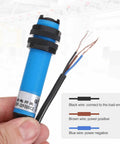 Hand holding Industrial Grade Photoelectric Sensor M18 Diffuse Reflection, Three-Line Detection Range 200cm, with wire connections visible