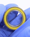 Close-up of Ceramic Hybrid Radial Bearing for Bike Hubs 15x24x5mm, featuring yellow seal with 2RS marking and gloved hand.