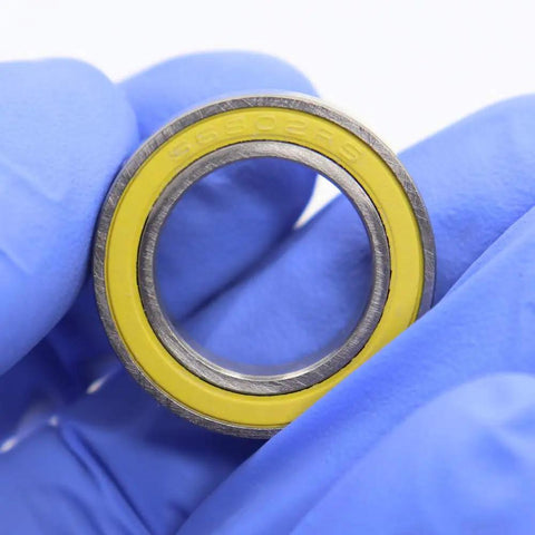 Close-up of Ceramic Hybrid Radial Bearing for Bike Hubs 15x24x5mm, featuring yellow seal with 2RS marking and gloved hand.