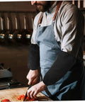 Six Pairs Oil Resistant Arm Sleeves Long Kitchen Cooking Oversleeves With Grippy Elastic Bands Keeping Your Clothes Clean During The Daily Hustle Straight Up Heavy Duty Material That Repels Oil Like A Pro, worn by a chef in a kitchen chopping vegetables.