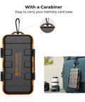 Rugged Water Resistant Camera Battery And Card Case with carabiner attached to a blue backpack, showing secure portability.