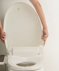 Person lifting the lid of a Straight Up Comfort Heated Bidet Toilet Seat in durable off-white design.