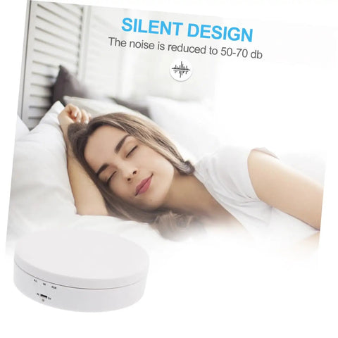 White Electric Rotating Display Stand For Jewelry Watches And Cosmetics Automatic Turntable Showcase with a person sleeping peacefully nearby.