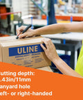Slice 10513 pen cutter with black handle cutting a cardboard box in a warehouse; manual blade