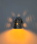 Silver Brass Wall Sconce, Mid Century Cone Lamp, Perforated Spotlight casting warm light and intricate shadows on a wall.