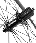 Close-up of Carbon Fiber Road Bike Wheelset 700C Clincher hub, 11-speed design with spokes, part of Bombproof Toray T700C Build, UCI Approved.