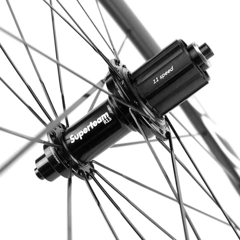 Close-up of Carbon Fiber Road Bike Wheelset 700C Clincher hub, 11-speed design with spokes, part of Bombproof Toray T700C Build, UCI Approved.