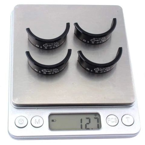 Four black Aluminum Alloy Handlebar Shims 31.8mm to 35mm on scale displaying 12g