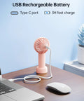 Mini Portable USB Rechargeable Handheld Fan, 3 Speeds, Cute Pink Travel Companion charging via laptop Type-C port on desk.