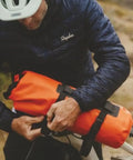 Cyclist attaching Spider Handlebar Cradle With 8L Heavy Duty Dry Bag For MTB Gravel And EMTB Bikes Quick Release Mount
