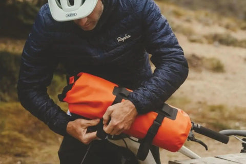 Cyclist attaching Spider Handlebar Cradle With 8L Heavy Duty Dry Bag For MTB Gravel And EMTB Bikes Quick Release Mount