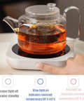 Keep Those Daily Brews Popping With This Touch Control Coffee Mug Warmer And Electric Cup Heater Featuring a tea kettle on a warmer with visible temperature indicators.