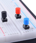 84 Pcs Momentary Tactile Push Button Switch Kit 6x6x8mm With 7 Color Button Caps Black Red Blue Yellow White Green Gray 12 Pieces Each For Breadboard Arduino Prototyping And DIY Electronics Projects showing black, red, and blue switches on breadboard