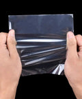 Hands holding a 4 X 4 Inch Heat Shrink Bag made of slick glossy polyolefin film, showcasing its flexibility.