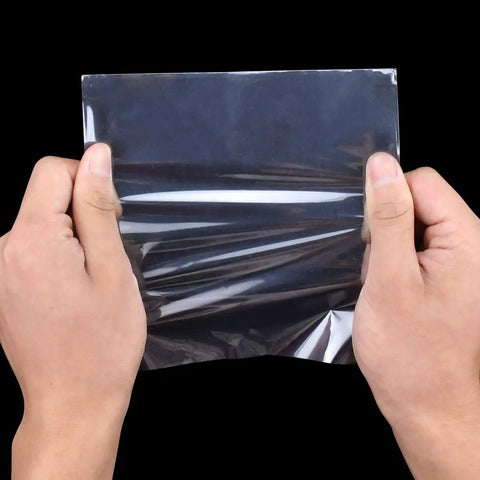 Hands holding a 4 X 4 Inch Heat Shrink Bag made of slick glossy polyolefin film, showcasing its flexibility.