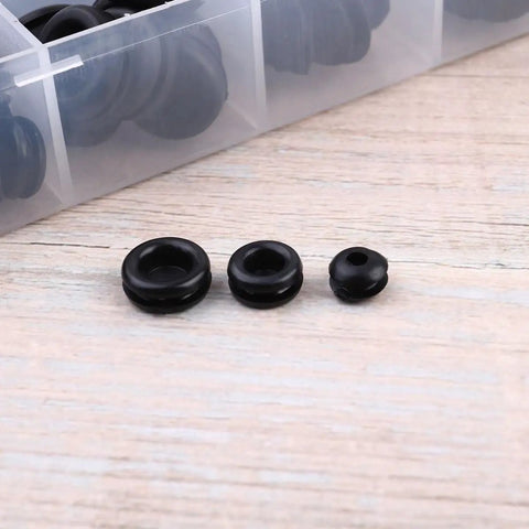 Grommet And Seal Kit With 125 Pieces, Black Ring Rubber Grommets And Seals For Auto And Home Appliance Hoses Faucets And Wiring, DIY Friendly, Heat Resistant Ultra Elastic Pollution Free Plastic Box Included. Three black rubber grommets on wood with storage box