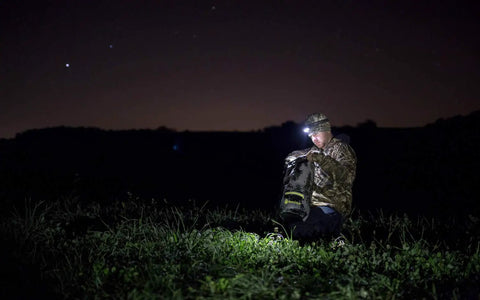 Person using DrySak Roll Top Waterproof Bag 5L Tie Dye at night outdoors, showcasing its gear protection for adventure.