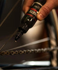 Hand applying Synergetic Bike Chain Lube Wet Lube 2oz Bottle With Premium Synthetic Oil And ZDDP WS2 Blend to bicycle chain