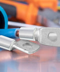 Close-up of heavy-duty battery cable terminals on a reflective surface with blurred background, showcasing metal components and insulation.