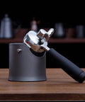 Heavy Duty Shock Absorbent Coffee Knock Box For Espresso Machines with a metal portafilter resting in the black base.