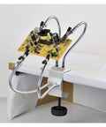 Four Arm Third Hand Soldering Station With Adjustable Gooseneck Arms holding a PCB for repair, aluminum base, black welding stand.