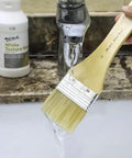 Brush being rinsed under tap water with Premium White Texture Gesso 250ml For Artists Pro Grade Primer in the background.