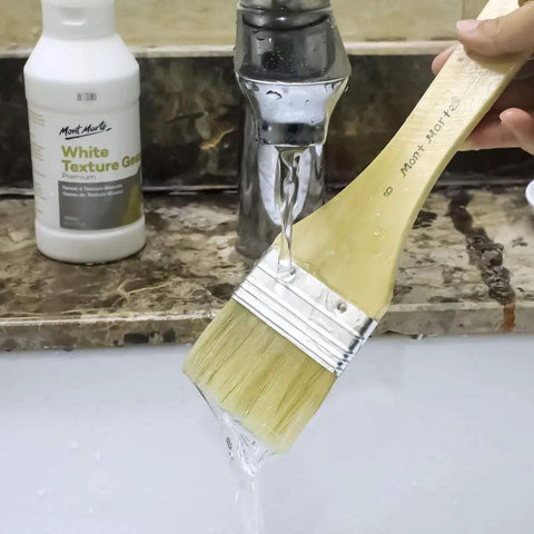 Brush being rinsed under tap water with Premium White Texture Gesso 250ml For Artists Pro Grade Primer in the background.