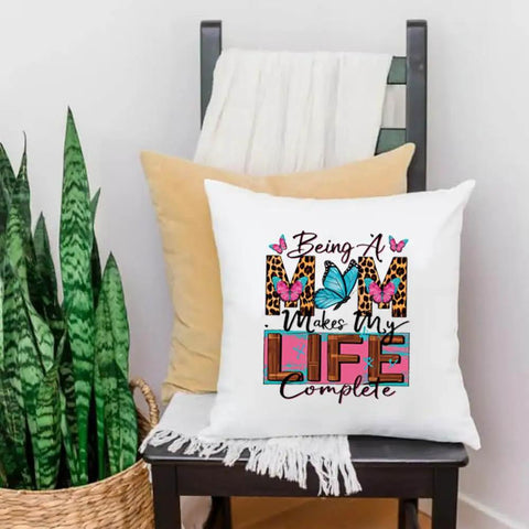 Chair with a pillow featuring 'Being a Mom Makes My Life Complete' in floral and leopard print. Four Pack Iron On Transfers For T Shirts DTF Ready To Press Easy To Apply With Any Home Iron Or Heat Press Floral Mama Leopard Print Designs For Clothes Pillows Bags And DIY Crafts Assorted Sizes.