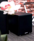 Shaker 8 Inch Powered Subwoofer With 400W Peak 200W RMS Class D Amplifier in a modern living room setting next to furniture.
