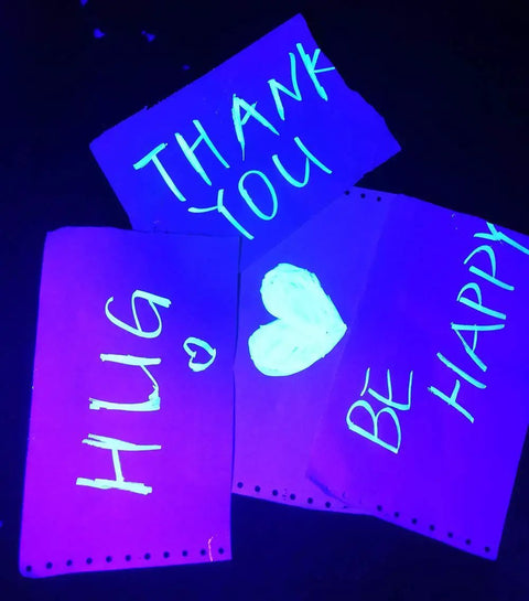 Fluorescent posters under 8W UV LED black light with glowing neon words: Thank You, Hug, Be Happy, & Heart symbol.