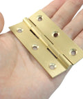 Built Rock Solid 3 Inch Mini Brass Hinges in hand, showcasing solid construction for cabinet upgrades.