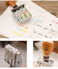 Premium Roller Date Stamp With Comfortable Wood Handle And Secure Grip Base Straight Up on planner with colorful dates stamped.