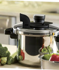 Pressure cooker with a silicone diverter hose for steam control, surrounded by fresh vegetables on a kitchen counter.