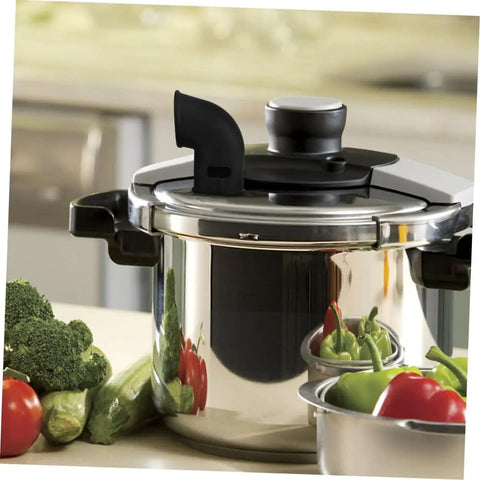 Pressure cooker with a silicone diverter hose for steam control, surrounded by fresh vegetables on a kitchen counter.