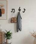 Fresh Black Cast Iron Musical Note Wall Hooks Set Of Three Decorative Coat Rack With Mounting Screws Hanging Clothes Bags And Keys In Music Room Or Kitchen Vibe, displaying a bag and jacket.