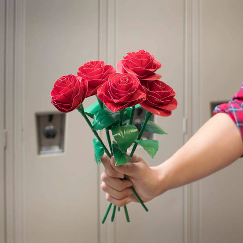 Hand holding a bouquet of roses crafted from duct tape in front of lockers.