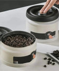 Heavy Duty Glass Storage Jars With Kickass Vacuum Seal Technology storing coffee beans on a white surface, featuring a lid and easy access.