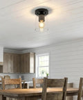 Industrial Semi Flush Mount Ceiling Light With Cylinder Glass Shade And E26 Base installed in a kitchen with black matte finish.