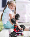 Child wearing Kids Protective Gear Set Knee Elbow And Wrist Guards For Roller Skating Skateboarding BMX Cycling Inline Skating And Scooter Riding Size Medium Black Durable 3 Piece Safety Gear For Beginners, sitting with roller skates outdoors.