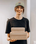 Person wearing Apricot Baseball Cap For Men Camp Hat Sun Shield With Printed Design holding gift boxes indoors.