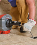 Heavy Duty Cordless Drain Snake With Brushless Motor And Twenty Five Foot Steel Cable Blasts Away Stubborn Clogs being used on a shower drain.