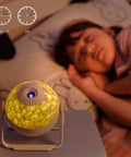 7 In 1 Planetarium Projector For Kids Room Decor with HD Focus, 360 Degree Rotating Ceiling Night Light next to sleeping child