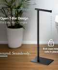 Modern Square Base Toilet Paper Holder Stand In Matte Black No Drill Install Free Weighted And Padded Base For Stable Rust Resistant Metal Bathroom Accessory 22.25 Inch Tall shown on bathroom floor with plant in background.