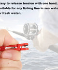 Front view: YUNNLEZT downrigger release clip, red, held by hand with fishing rod over the ocean
