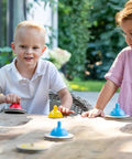 Children playing with Wooden Table Curling Set for Indoor Fun, 8 colorful stone pieces on the table in a garden setting.