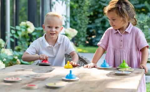 Children playing with Wooden Table Curling Set for Indoor Fun, 8 colorful stone pieces on the table in a garden setting.